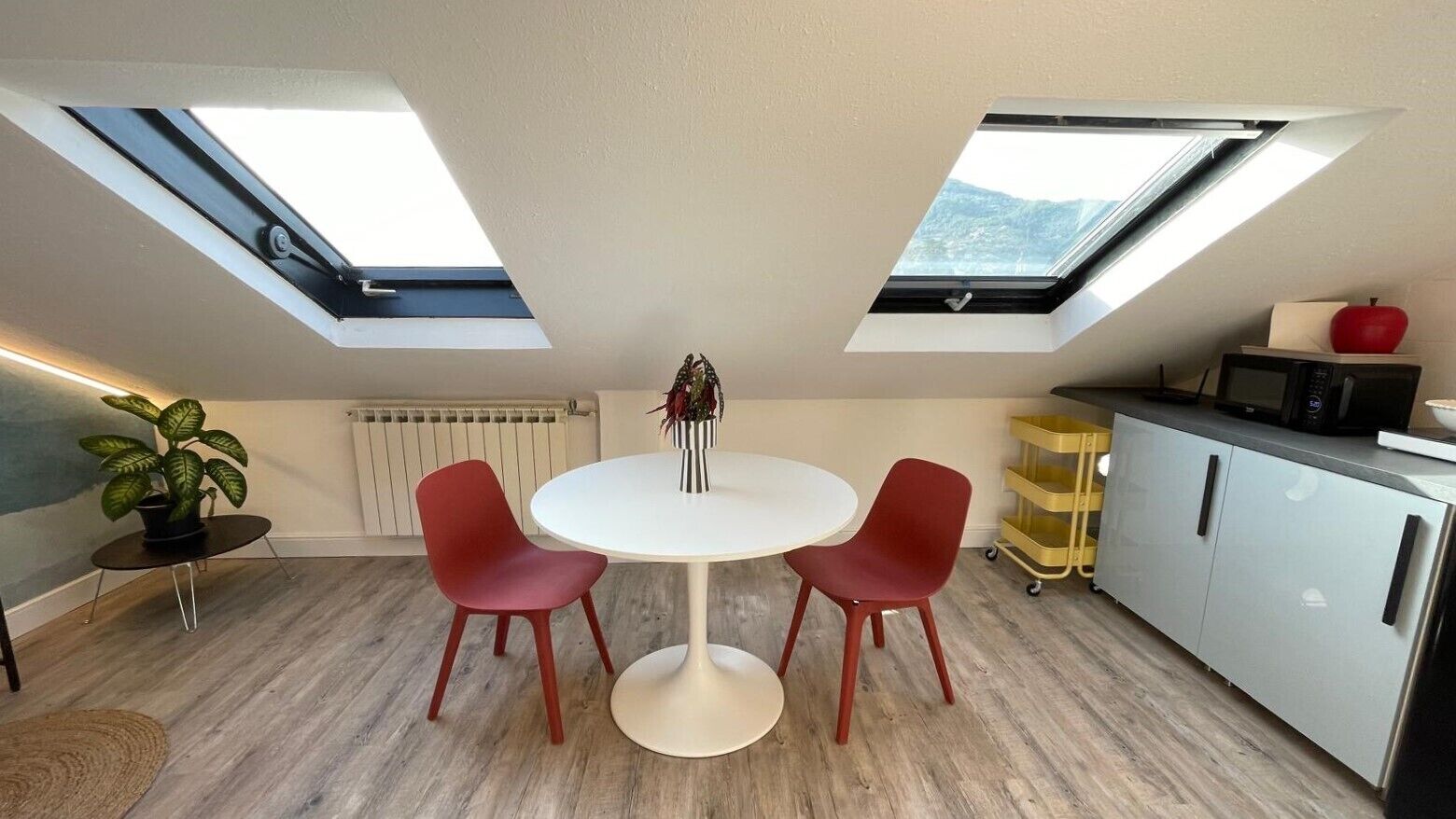 Cocina compacta con comedor, tragaluces y vistas al exterior.