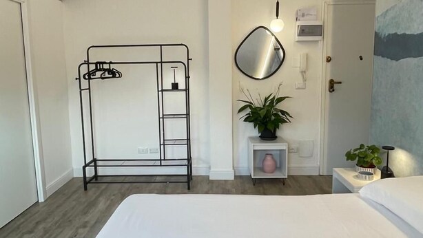 Een hotelkamer met een stapelbed, een nachtkastje met een lamp, een potplant en een schilderij aan de muur.