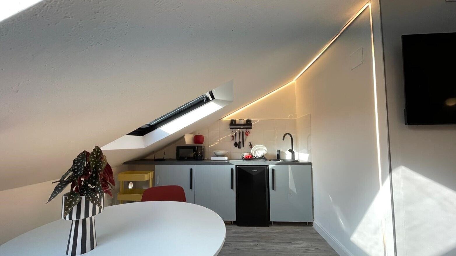 A compact kitchen with a modern design, featuring a microwave, toaster, and sink.