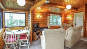 L’intérieur d’une cabane en rondins comprend un coin repas, un canapé et un téléviseur.