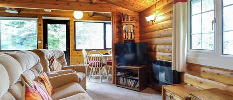 A cozy log cabin interior with a sofa, television, and bookshelves.