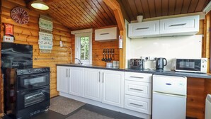 Une cuisine de taille réduite avec des meubles blancs, un four noir, un four à micro-ondes et un grille-pain.