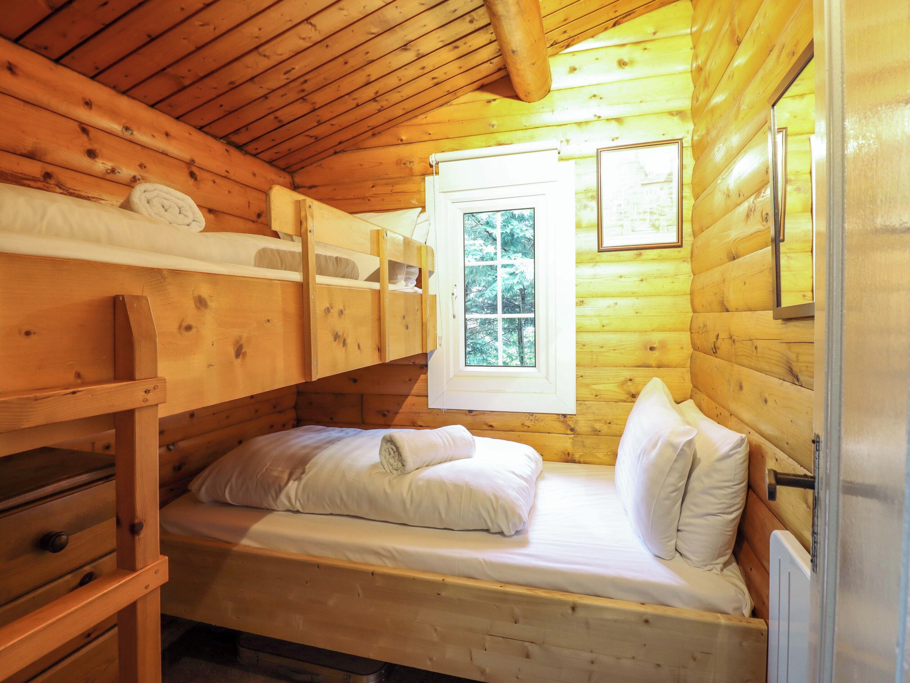 Ein Zimmer einer Holzhütte mit Etagenbetten, einem Fenster und einer Heizung.