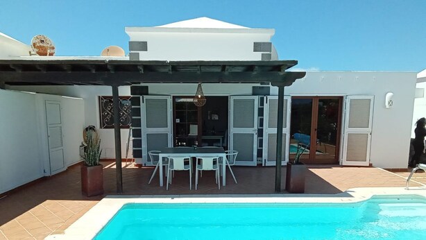 Une piscine dotée d’une pergola et d’un espace salon extérieur.
