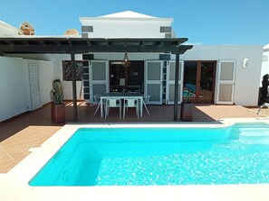 Une piscine dotée d’une pergola et d’un espace salon extérieur.