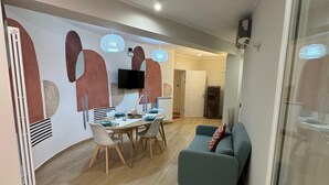 Un salon moderne comprenant un coin repas, un canapé et un téléviseur fixé au mur.