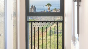 Un pasillo que conduce a un balcón con vistas al mar y formaciones rocosas.