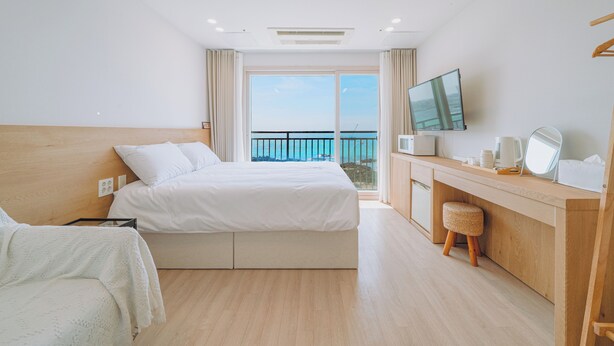 Una habitación de hotel moderna con una cama grande, un escritorio con ordenador, televisión y vistas al mar.