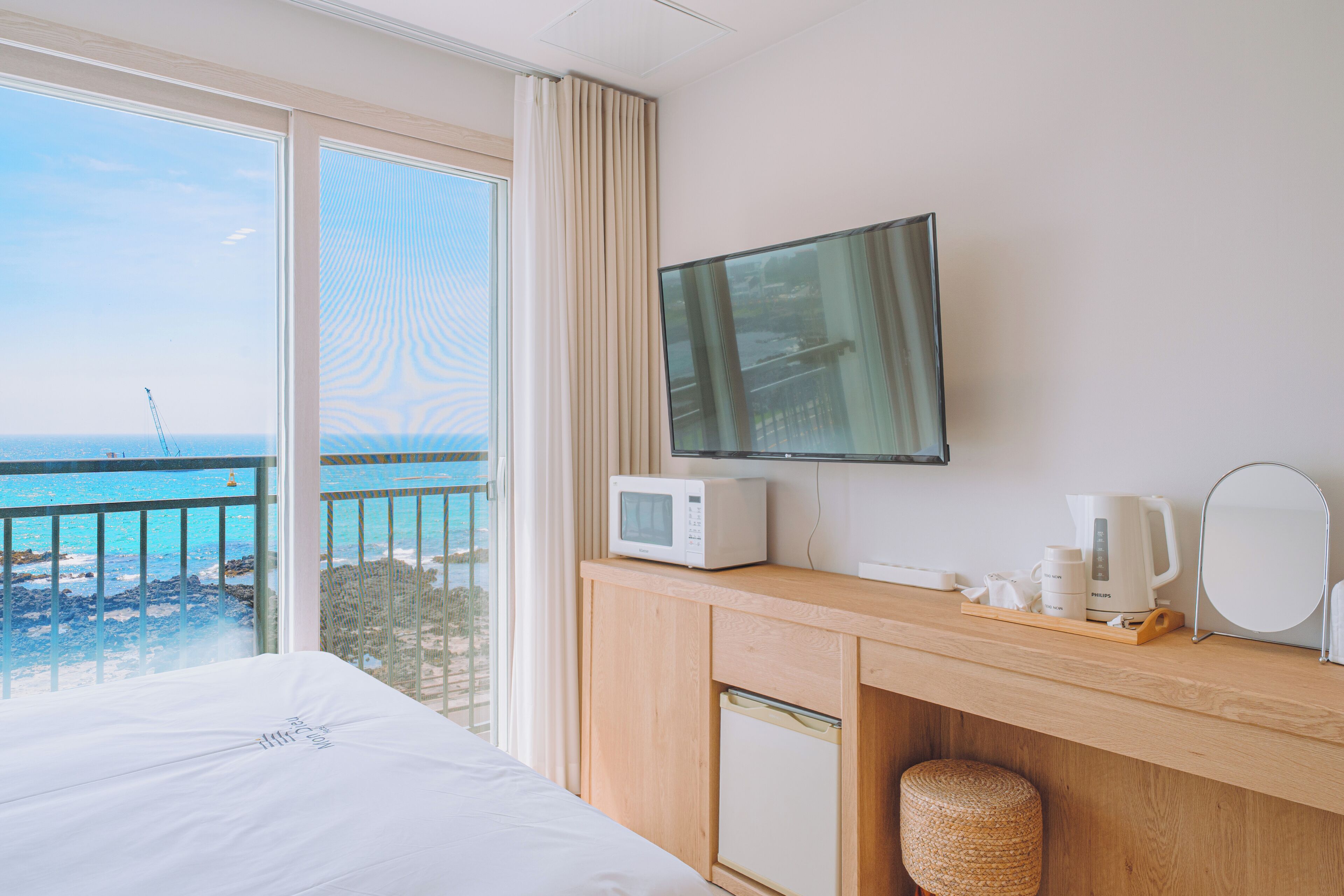 A hotel room with a bed, a desk with a microwave, a coffee maker, and a TV.