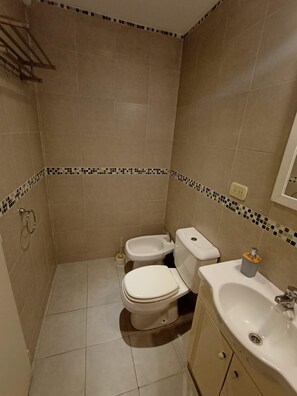 A small, tiled bathroom with a toilet, bidet, and sink.
