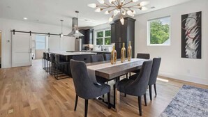 Een moderne keuken met een centraal eiland, donkere kastjes en een moderne kroonluchter.