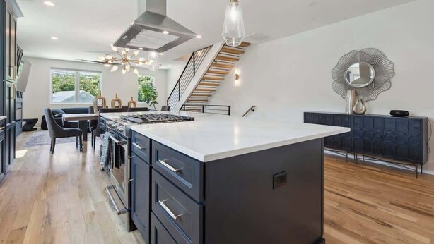 Een moderne keuken met een centraal eiland, een eetgedeelte en een trap naar een hoger gelegen verdieping.