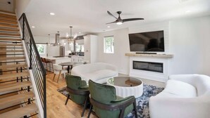 A modern living room with a staircase, a dining area, and a fireplace. - Luxury Build - King Beds - Minutes to Uptown (Charlotte)