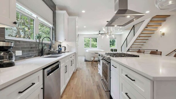 A modern kitchen with white cabinetry, a central island, and a staircase leading to an upper level. - Luxury Build - King Beds - Minutes to Uptown (Charlotte)