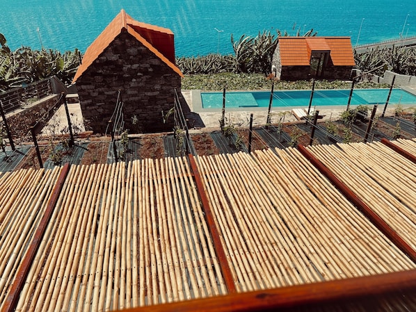 A wooden deck with a pool and a stone building in the background. - CASAS DO LARANJO- Cottages Infinity Pool by brugrani (Santa Cruz)