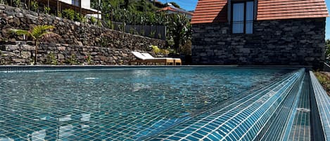 Una piscina al aire libre, sillones reclinables de piscina