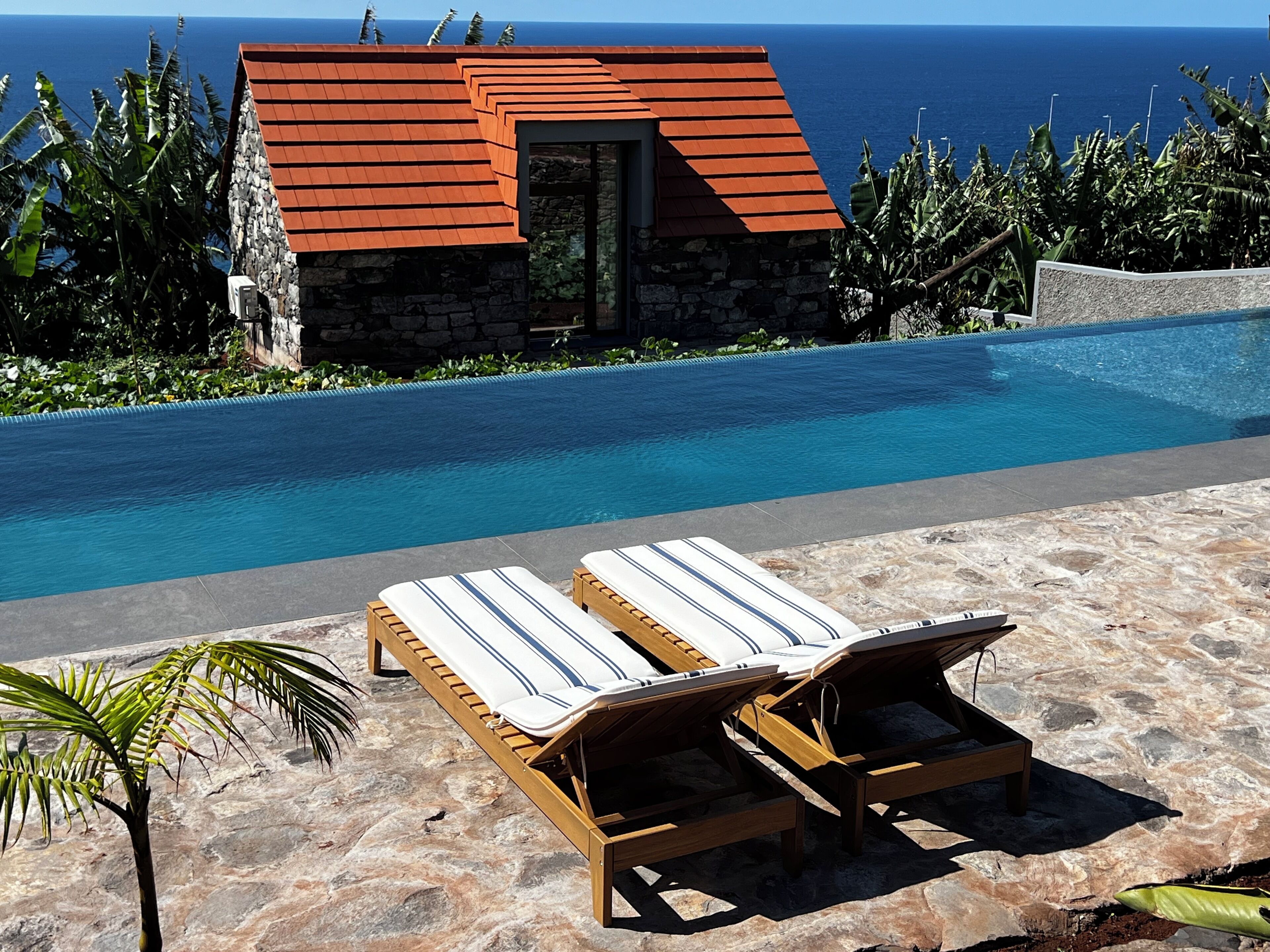 Una piscina al aire libre, sillones reclinables de piscina