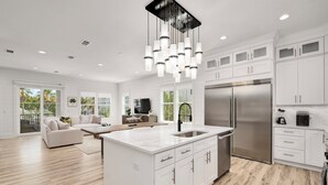 A modern kitchen with white cabinetry, a stainless steel refrigerator, and a central island. - Sea La Vie: Private Beach, Golfcart, Heated Pool & Hot Tub, Game Room, Bunk Room (Miramar Beach)