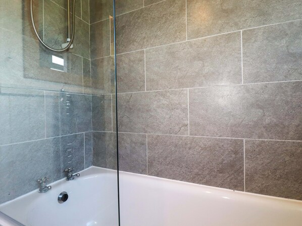 A modern bathroom with a bathtub, a glass shower enclosure, and tiled walls. - The Studio (Truro)