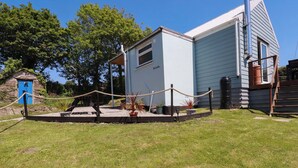 A small, light blue building with a flat roof, surrounded by a rope barrier and potted plants. - The Studio (Truro)