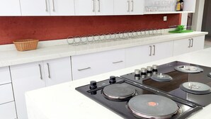 A modern kitchen with white cabinets, a black stove, and a red backsplash.