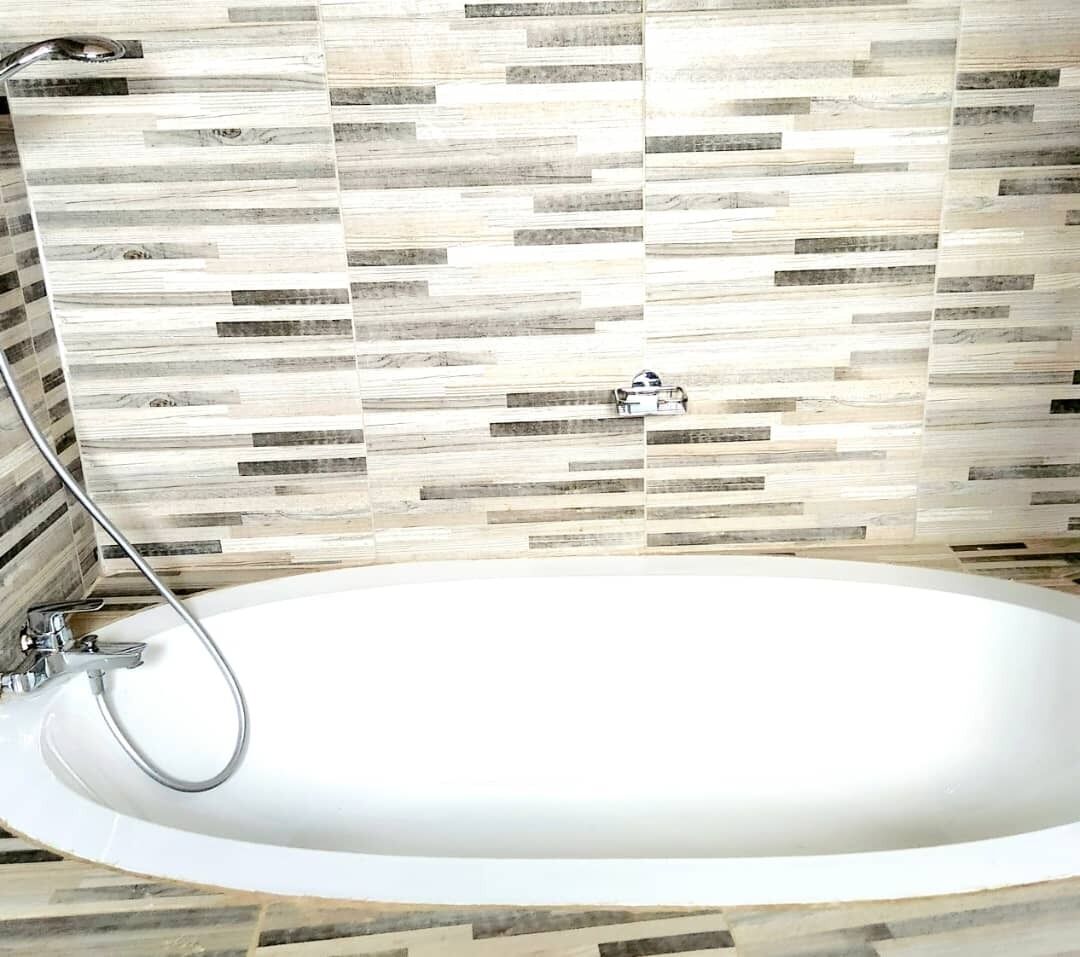 A modern bathroom with a freestanding bathtub, a shower, and a tiled backsplash.