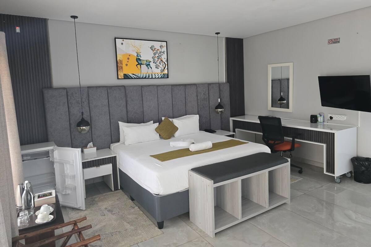 Una habitación de hotel moderna con cama, escritorio y televisor.
