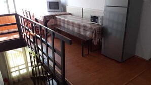 A kitchen with a table, chairs, a microwave, and a refrigerator. - Pensiunea Szurdok - Antonia Panzió (Baile Tusnad)