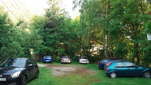 A parking area with several cars parked on grass, surrounded by trees. - Pensiunea Szurdok - Antonia Panzió (Baile Tusnad)