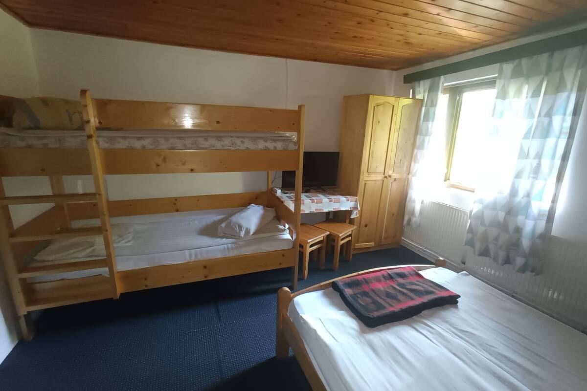 Ett rum med våningssängar, ett skrivbord och ett fönster med gardiner.