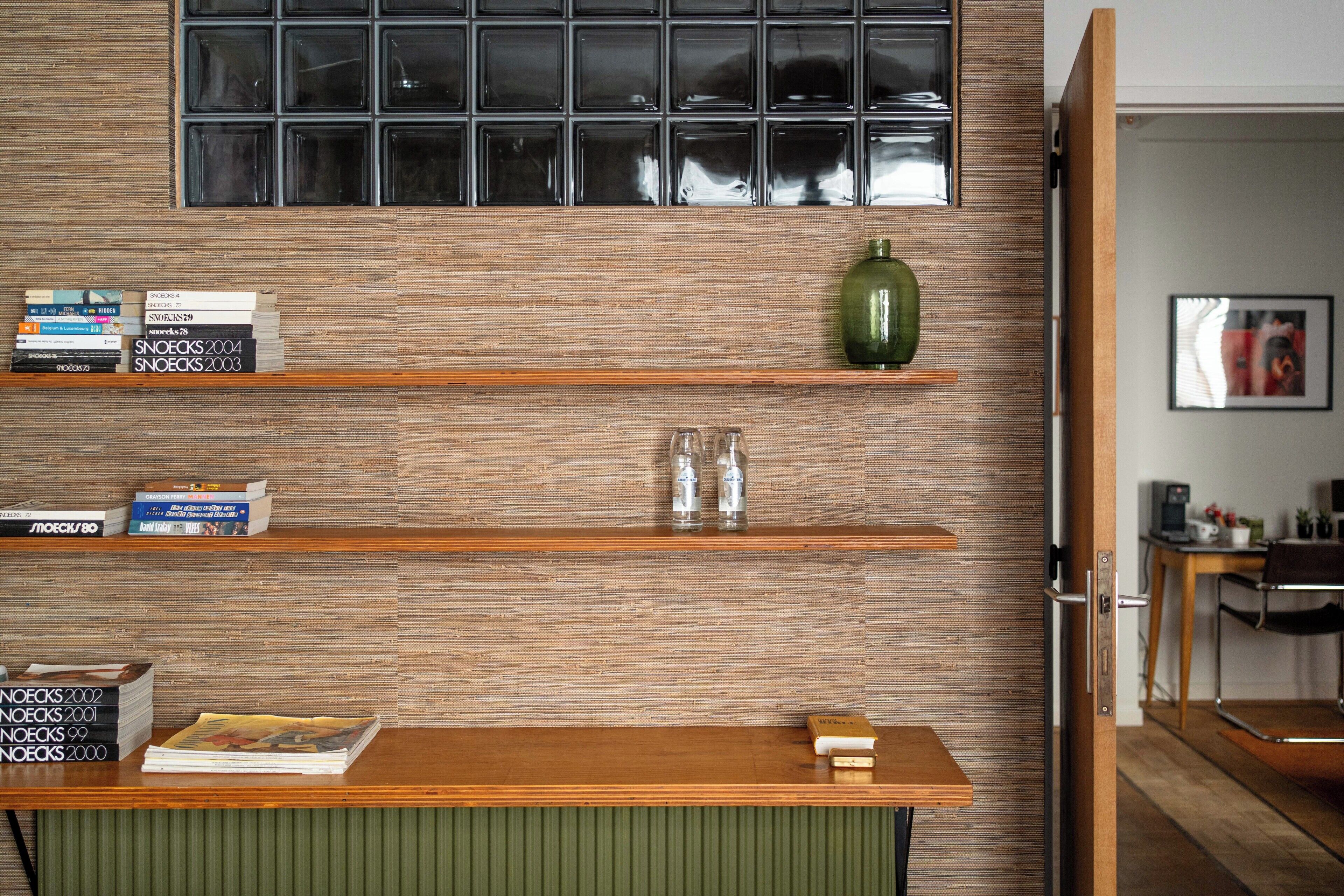 A reception desk with a wooden finish, a green vase, and a window with a grid pattern.