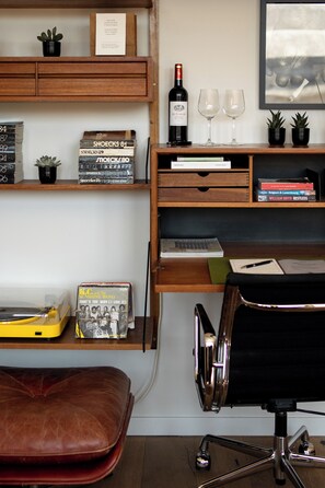 A room with a desk, shelves with books and records, a wine bottle, glasses, and a framed picture on the wall. - A place - Vrijdagmarkt 1 (Antwerp)