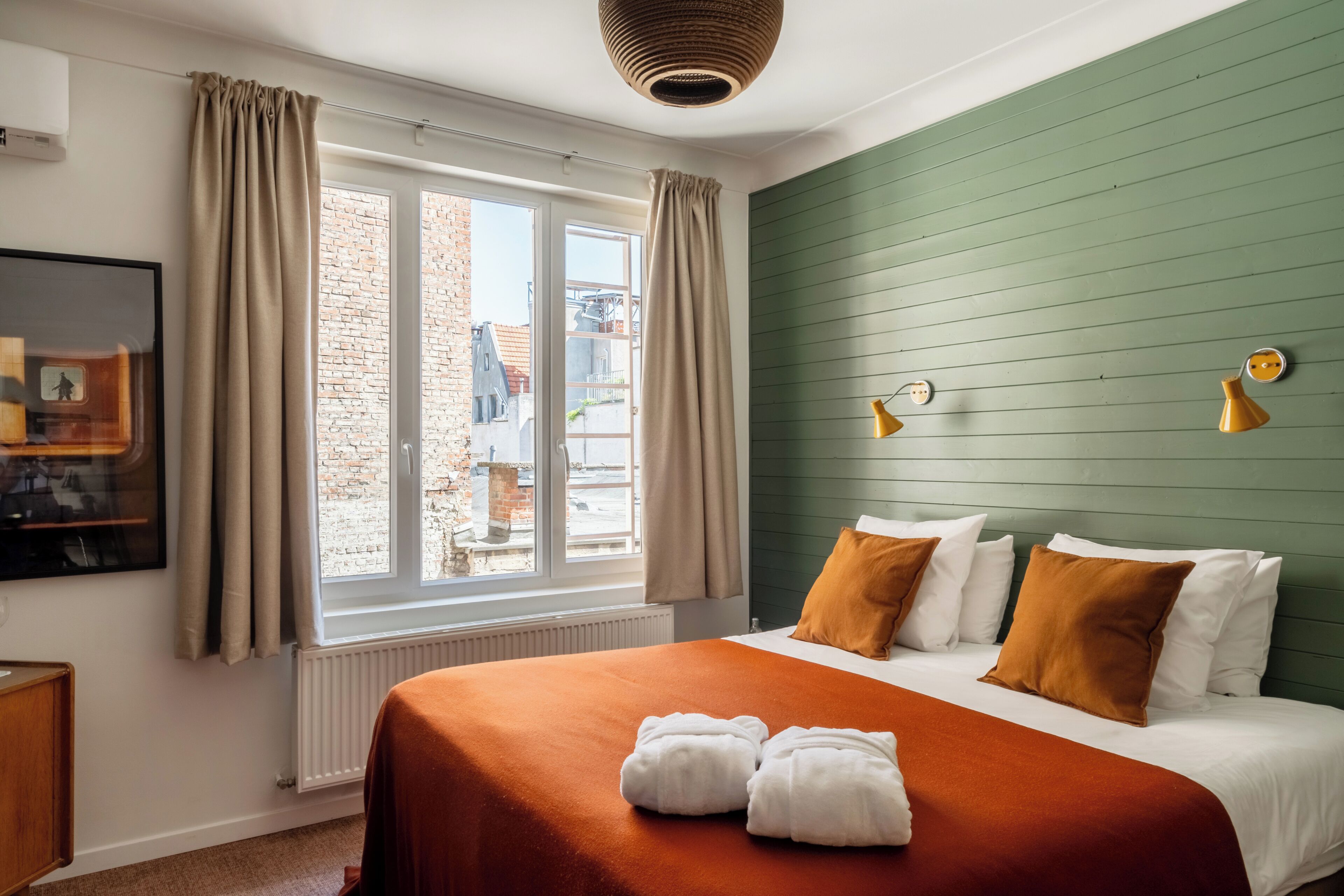 Una habitación de hotel con una cama grande, vistas de la ciudad a través de la ventana y una pared verde.