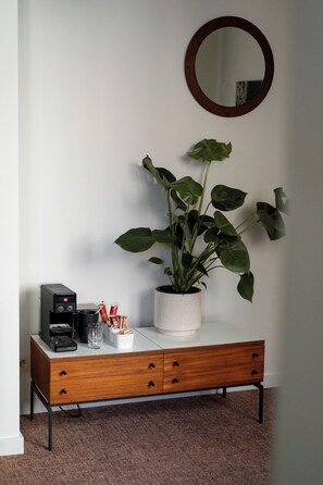 A small wooden cabinet with a coffee machine, a potted plant, and a mirror on the wall. - A place - Vrijdagmarkt 1 (Antwerp)