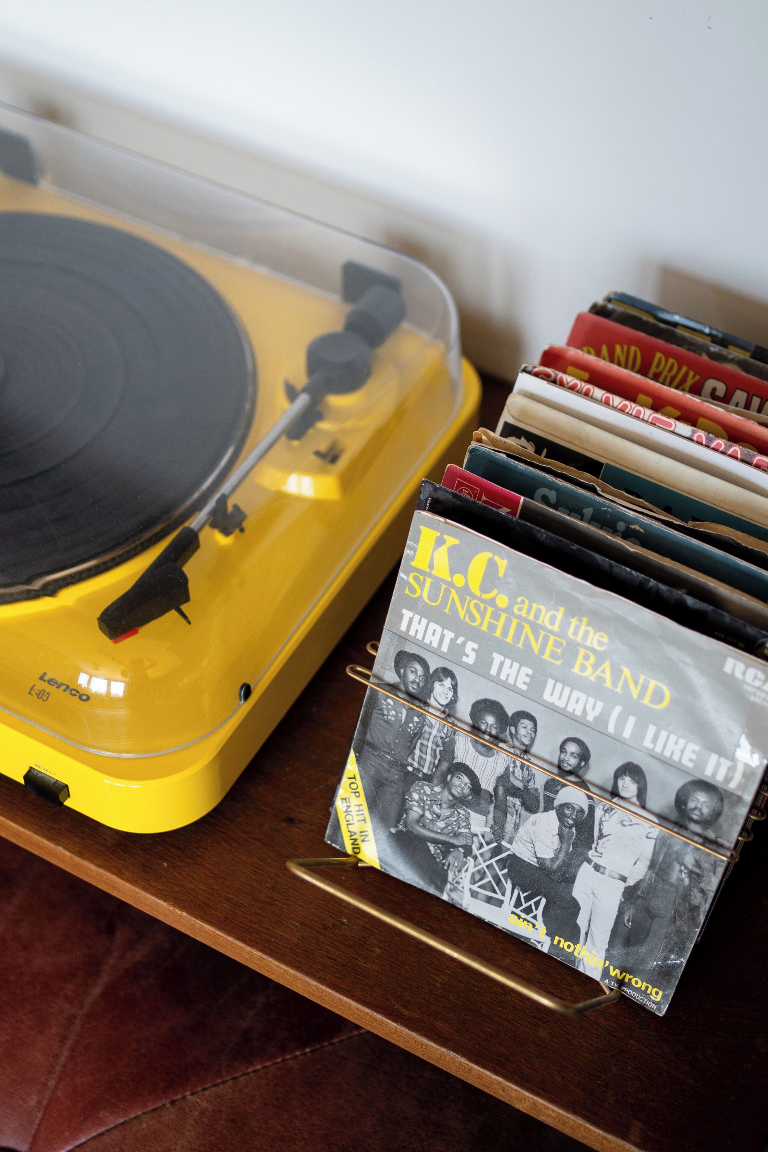 A yellow turntable with vinyl records and a CD case with band photos.
