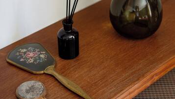 Una mesa de madera con un florero verde, un quemador de incienso negro, un abanico decorativo y un espejo redondo pequeño.