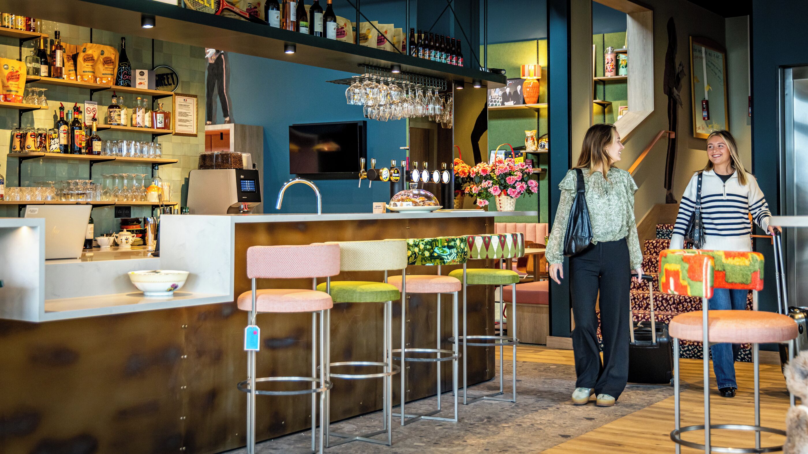 A bar area with stools, shelves with bottles, and a counter.