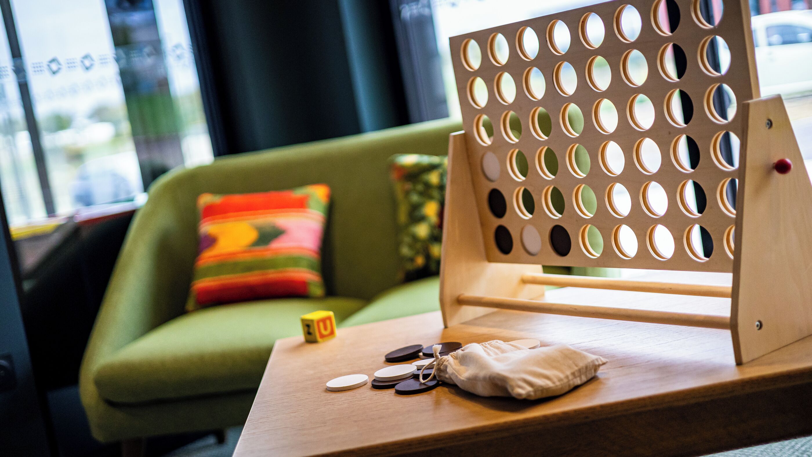 Une table en bois, un panneau perforé, un coussin, un petit sac et quelques pièces de monnaie.