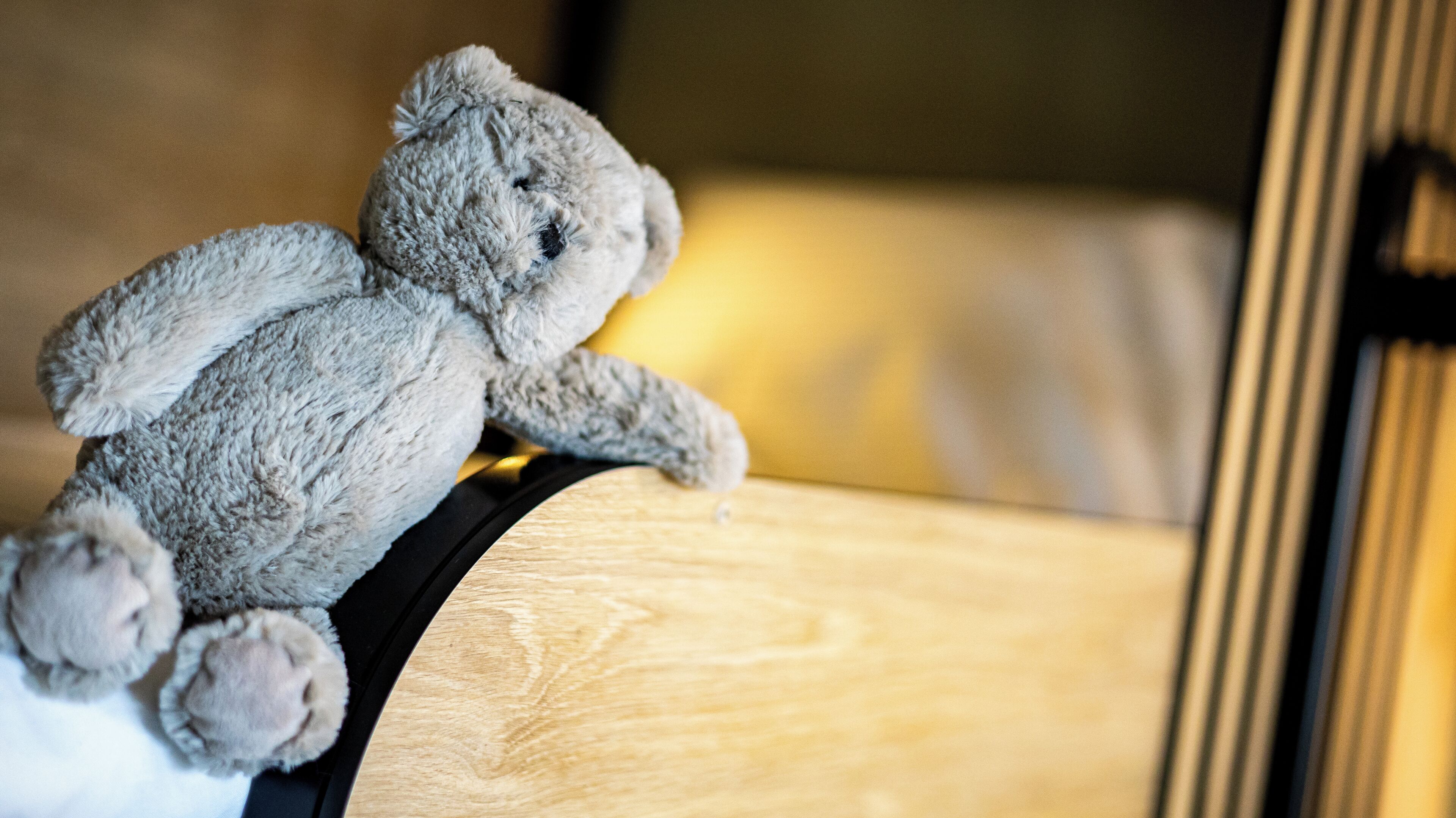 Un jouet en peluche posé sur une surface en bois, peut-être un lit ou un canapé.