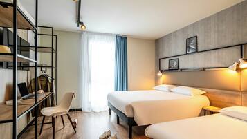 Een hotelkamer met twee bedden, een bureau met een laptop, een stoel en een kledingkast.