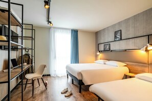 A hotel room with two beds, a desk with a laptop, a chair, and a wardrobe. - ibis Bordeaux Nord Carbon Blanc (Carbon-Blanc)