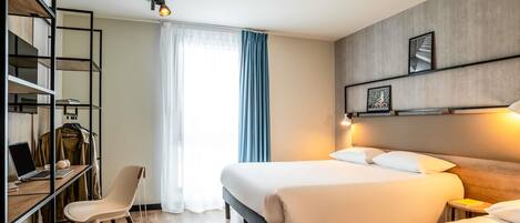 Een hotelkamer met twee bedden, een bureau met een laptop, een stoel en een kledingkast.