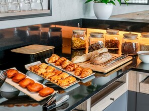 Un buffet della colazione con pasticcini, pane e diversi cibi presentati in vasetti.