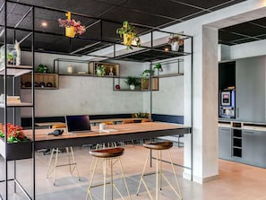 A modern office space with a long table, multiple chairs, a laptop, and a coffee machine.