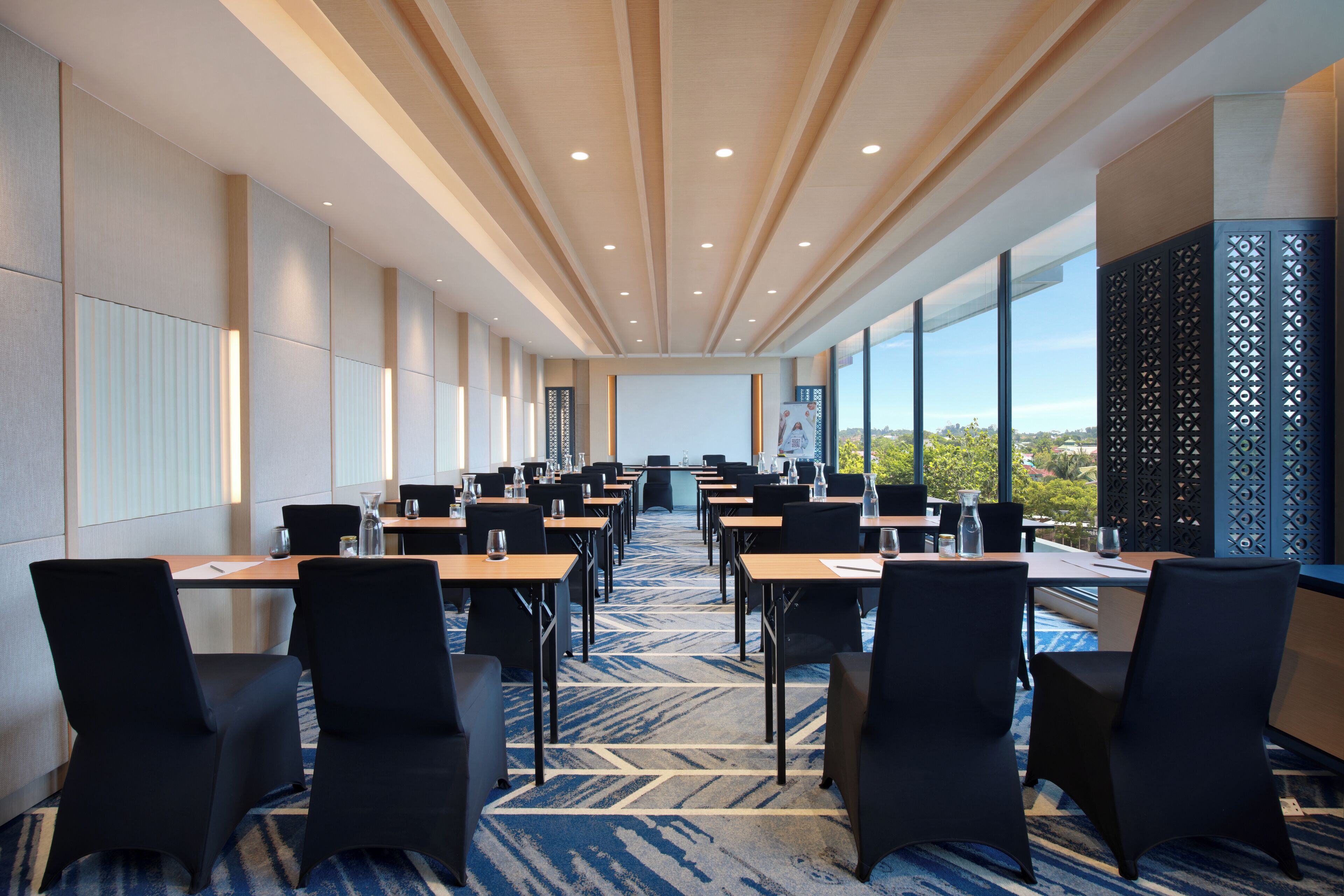 A conference room with a long table, chairs, and a large window with a view.