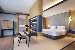 Una habitación de hotel moderna con cama, escritorio, silla y estanterías.