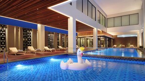 An indoor swimming pool with a swan float, lounge chairs, and a modern interior design. - Mercure Berau (Tanjung Redeb)