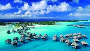 An overwater bungalows area with thatched roofs and clear turquoise waters. - Mercure Berau (Tanjung Redeb)