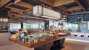 A modern breakfast bar with a variety of food items and a view of the city. - Mercure Berau (Tanjung Redeb)