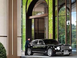 A black luxury car parked in front of a building with large windows and a green patterned wall. - Navera Phuket - Mgallery Collection (Choeng Thale)